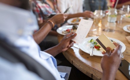 Mann an Esstisch möchte mit Karte bezahlen