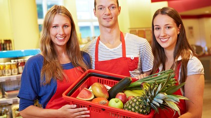 Mitarbeiter eines Supermarkts mit einem Korb Lebensmittel