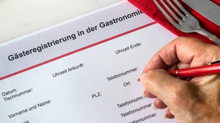 Nahaufnahme einer Person, die gerade eine Gästeliste im Restaurant ausfüllt