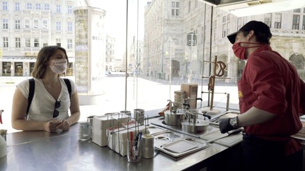 Würstelstand-Besucherin und -Mitarbeiter mit Mund-Nasenschutz