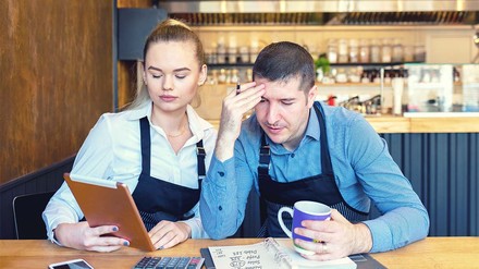 Gastronomen-Paar schaut verzweifelt auf ein Tablet