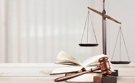 Waage, Gesetzbuch und Richterhammer auf einem Tisch