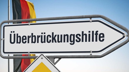 Wegweiser mit der Aufschrift Überbrückungshilfe