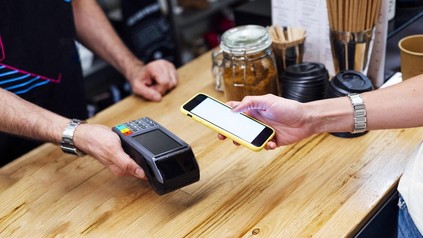 Gast zahlt im Café bargeldlos mit dem Smartphone