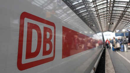 Ein Zug der Deutschen Bahn steht auf einem Gleis an einem Bahnhof.