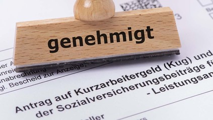 Antrag auf Kurzarbeit und ein Stempel mit der Aufschrift "Genehmigt"