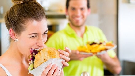 Eine Frau beißt herzhaft in einen Döner-Kebap.