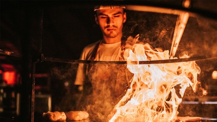 Ein Mann steht hinter dem Grill.