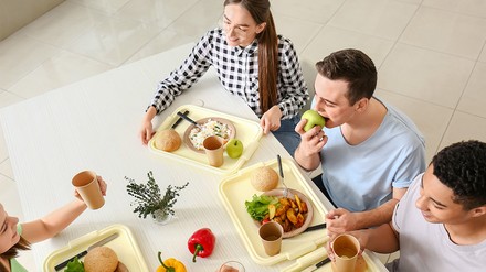 Studenten in Niedersachsen bekommen nun finanzielle Unterstützung, damit das Mensa-Essen wieder bezahlbar wird. (Foto: © Pixel-Shot/stock.adobe.com)
Studenten kommen beim Mittagessen in der Mensa zusammen.