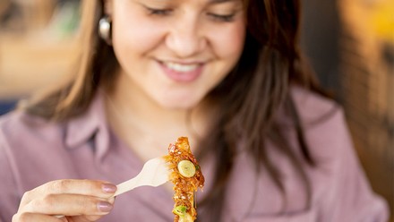 Eine Frau isst mit großer Freude ihre Portion Pommes.