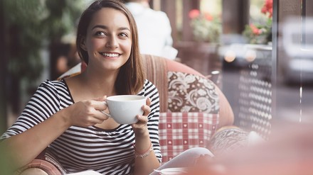 Eine junge Frau trink aus einer großen Kaffeetasse.