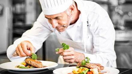Königlich kochen: Die Royals suchen einen neuen Souschef. (Foto: © vectorfusionart/stock.adobe.com) Ein Koch beim Anrichten seiner Speisen.