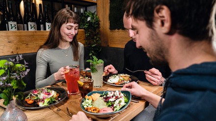 Cotidiano führt in allen Betrieben deutschlandweit eine neue Speisekarte ein. (Foto: © Cotidiano) Drei Freunde sitzen an einem Tisch und jeder von ihnen isst eine gesunde Bowl.