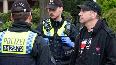 Der Fernsehkoch Ole Plogstedt steht bei einer Versammlungsauflösung neben Polizisten, die Personalien überprüfen. Aktivisten der Klimagruppe Letzte Generation wurden von Polizisten vor dem Hamburger Michel gestoppt. (Foto: © picture alliance/dpa/Bodo Marks | Bodo Marks) Der Fernsehkoch Ole Plogstedt steht bei einer Versammlungsauflösung neben Polizisten, die Personalien überprüfen. Aktivisten der Klimagruppe Letzte Generation wurden von Polizisten vor dem Hamburger Michel gestoppt.