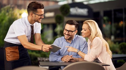 Digitale Anwendungen können den Angestellten wieder mehr Zeit geben, um sich wieder mehr um die Gäste kümmern zu können. (Foto: © Drazen/stock.adobe.com) Gäste bestellen via Tablet am Tisch mit dem Kellner