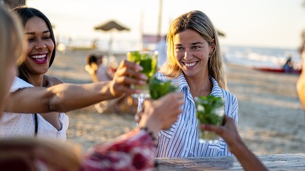 So lässt es sich Leben! (Foto: © MandriaPix / stock.adobe.com) Frauen genießen einen Cocktail an einer Strandar.