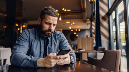 Gäste bewerten Restaurants negativer und extremer. Grund dafür ist oft eine ungenügende Serviceleistung. (Foto: © dusanpetkovic1/stock.adobe.com) Gast in einem Restaurant schaut verärgert auf sein Handy.