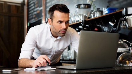 Der 30. Juni ist bei der Kurzarbeit und bei der Prüfung von Corona-Überbrückungshilfen ein wichtiges Datum. (Foto: © baranq/stock.adobe.com) Gastronom vor einem Computer