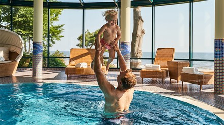 Mann hält Kind im Pool