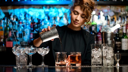 Der Lady Amarena Wettbewerb ist ein exklusiver Bartender-Wettbewerb für Barfrauen. Fabbri1905 möchte damit ein Zeichen setzten und die Gleichberechtigung zwischen Mann und Frau hinter der Bar fördern. (Foto: © fesenko/stock.adobe.com) Eine Bartenderin bereitet hinter der Bar einen Cocktail zu.