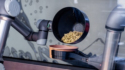 Der Kochroboter füllt ein fertiges Gericht in eine Schale. (Foto: © picture alliance/dpa | Markus Scholz) Kochroboter