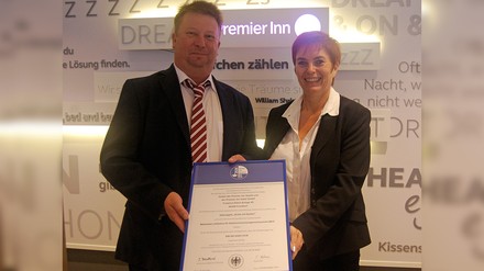 Tim Kleinecke, Berufsgenossenschaft Nahrungsmittel und Gastgewerbe BGN, (links) überreicht Inge Van Ooteghem, Chief Operating Officer bei Premier Inn Deutschland, das Gütesiegel „Sicher mit System“. (Foto: © Premier Inn Deutschland) Tim Kleinecke und Inge Van Ooteghem