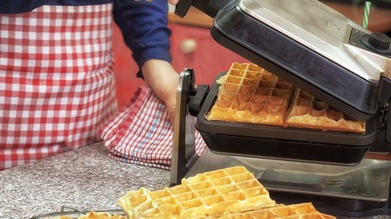 Genießer-Waffeln mit Blattgold für den verwöhnten Gaumen gibts am Stand der Manufaktur Neumärker. (Foto: © circleps/stock.adobe.com) Eine Person bereitet Waffeln mit einem Waffeleisen zu.