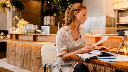 Bis zum 31. Oktober 2023 müssen alle Unternehmen, die während der Pandemie Corona-Hilfen bekommen haben, eine Schlussabrechnung einreichen. (Foto: © Drobot Dean/stock.adobe.com) Eine Gastronomin sitzt vor ihrem PC und geht die Abrechnung durch