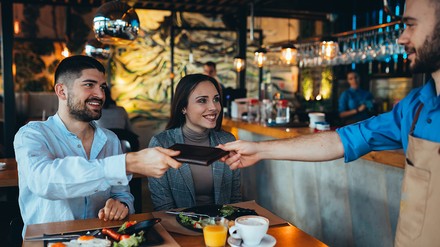 Deutsche sind laut einer Umfrage von YouGov großzügiger im Trinkgeldgeben als Schweizer. (Foto: © cherryandbees/stcok.adobe.com) Paar im Restaurant beim Bezahlen