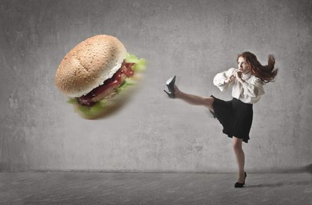 Eine Frau kickt einen großen Burger weg