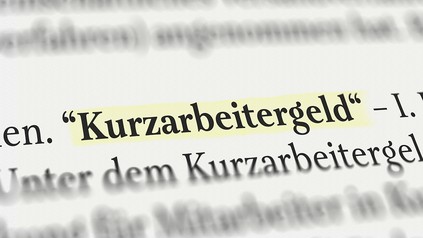 das Wort "Kurzarbeitergeld" im Buch gelb angemarktert