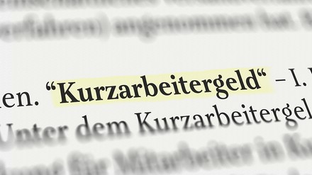 das Wort „Kurzarbeitergeld“ im Buch gelb angemarktert