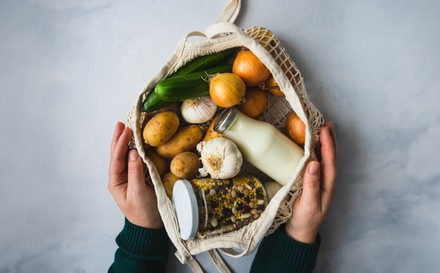 Zwei Hände halten einen Beutel mit Gemüse und Joghurt auf.