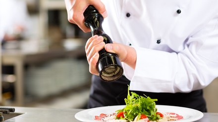 Koch, der eine Speise würzt