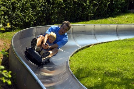 Mann mit Kind auf Sommerrodelbahn