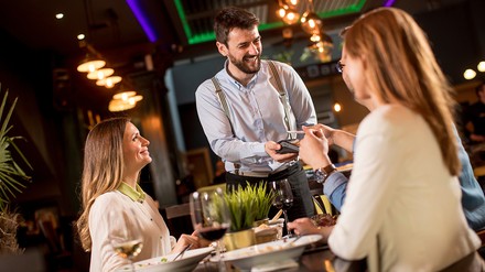 Kellner kassiert Gäste ab