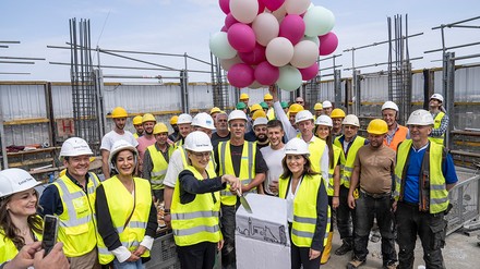 Die Bauarbeiter auf der Plattform des Towers mit Torte und Luftballons.