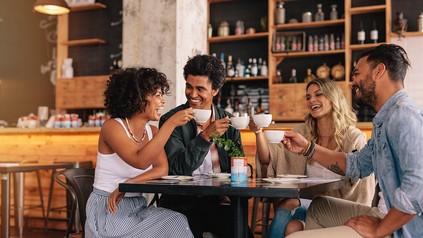 Vier junge Menschen sitzen an einem Tisch und trinken Kaffee