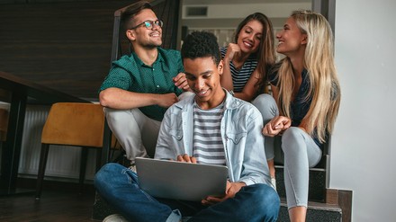 Vier junge Menschen sitzen dicht beieinander und arbeiten