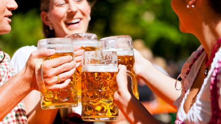 Vier Menschen stoßen mit Bierkrügen an