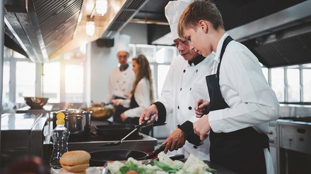 Koch zeigt einem Auszubildenden etwas