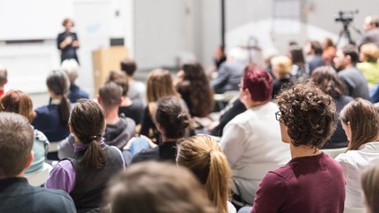 Frau präsentiert vor Gruppe in Universitätshalle