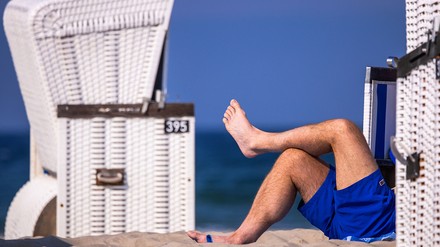 Männliche Beine ragen aus einem Strandkorb heraus