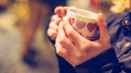 Mensch mit dampfender Tasse in der Hand