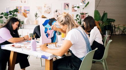 Junge Frauen sitzen an Tischen und malen