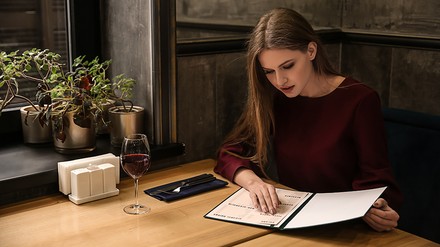 Frau schaut in eine Speisekarte