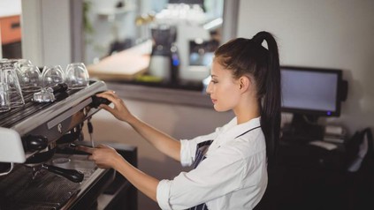 Eine junge Frau bereitet Kaffee zu
