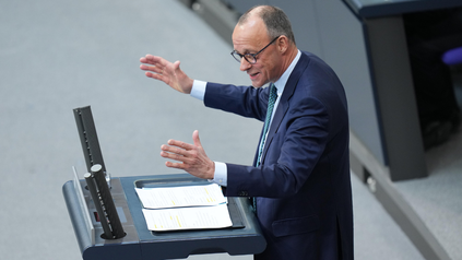 Der Spitzenkandidat der CDU, Friedrich Merz, steht im Bundestag am Rednerpult und gestikuliert mit seinen Armen