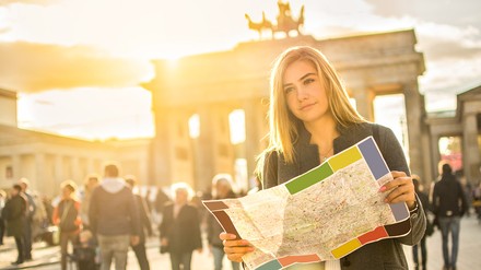 Frau steht mit Stadtplan vor dem Brandenburger Tor