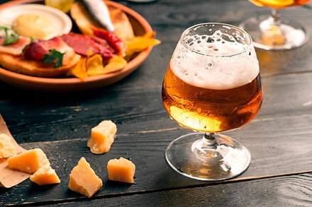 Ein Glas Bier mit einigen Delikatessen im Hintergrund